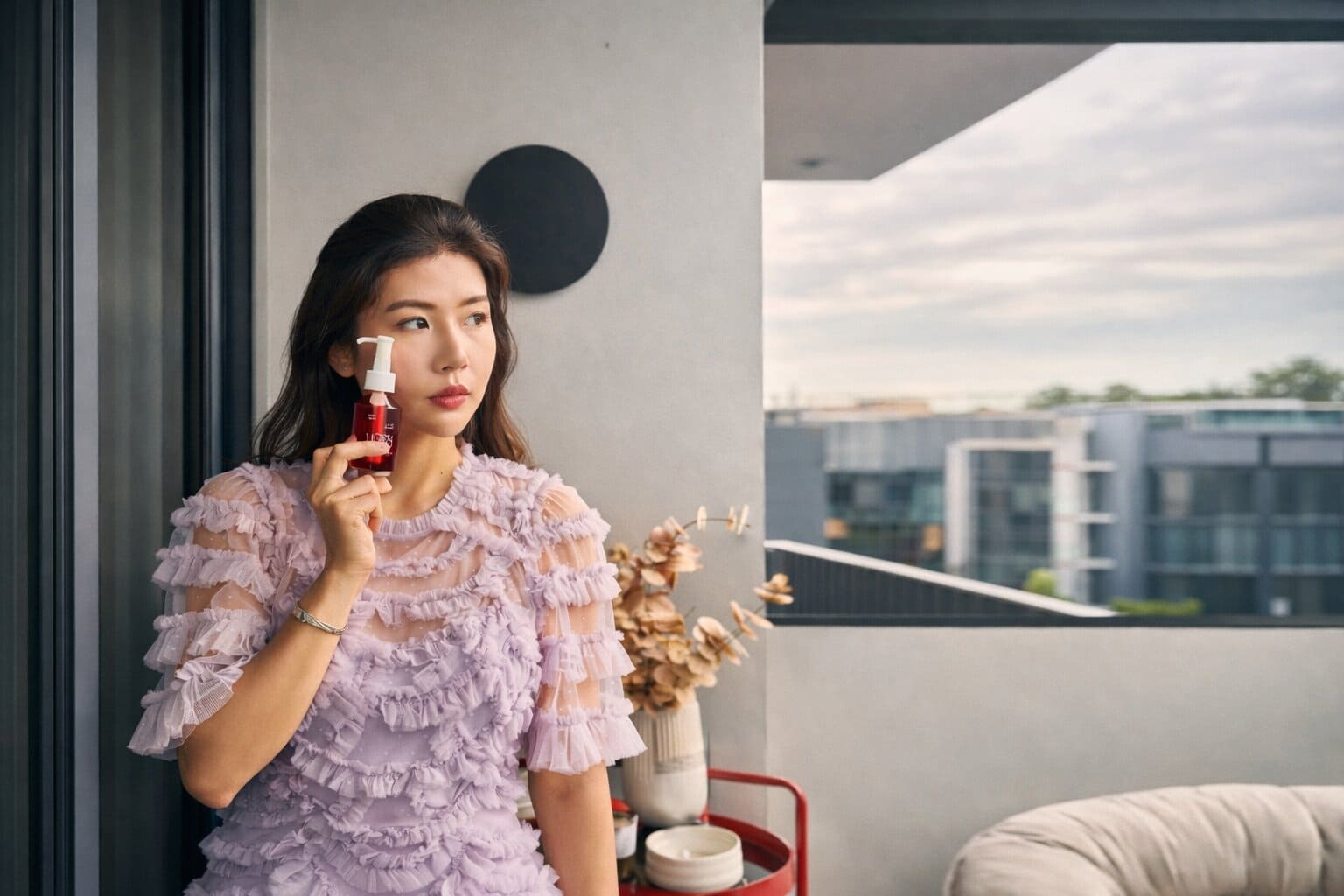 founder of the moon trace holding moon oil on a balcony with a cityscape view